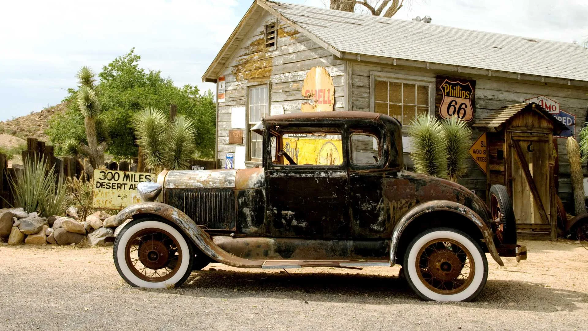 An old car is parked in front of a small house