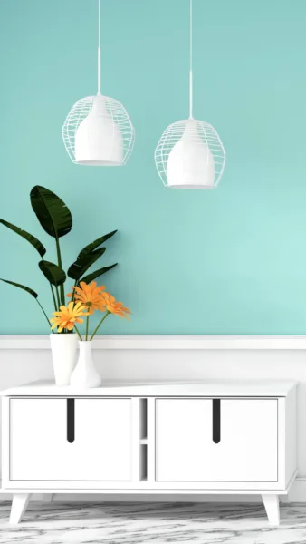 A vase of flowers and a lamp on a white cabinet