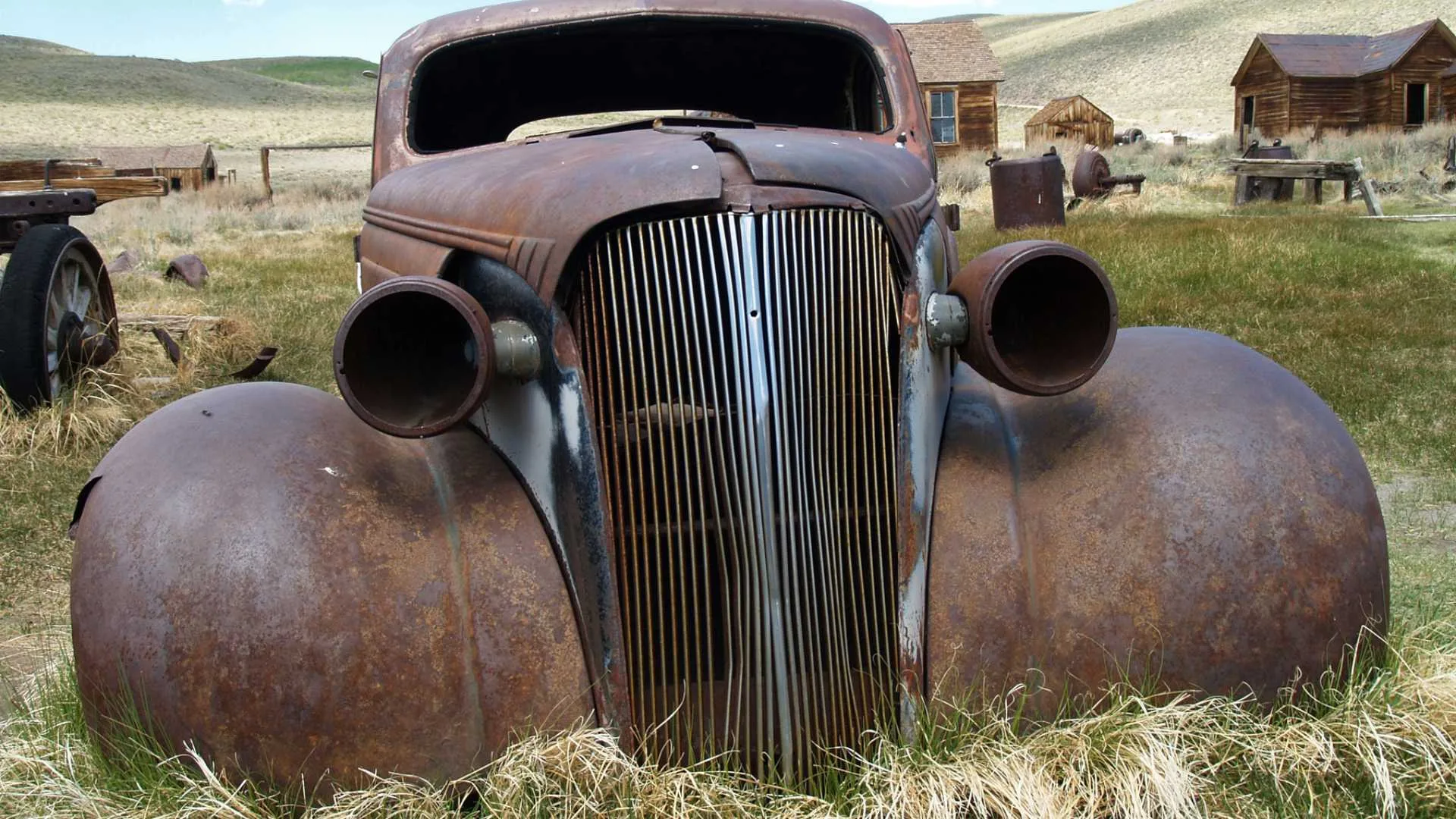 An old rusty car parked in the grass