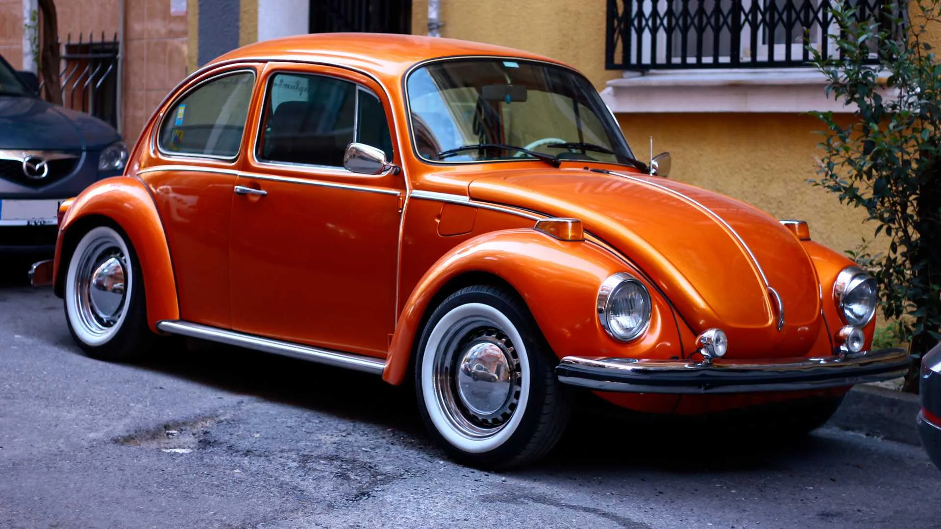 An orange Volkswagen Beetle is parked on the side of the road.