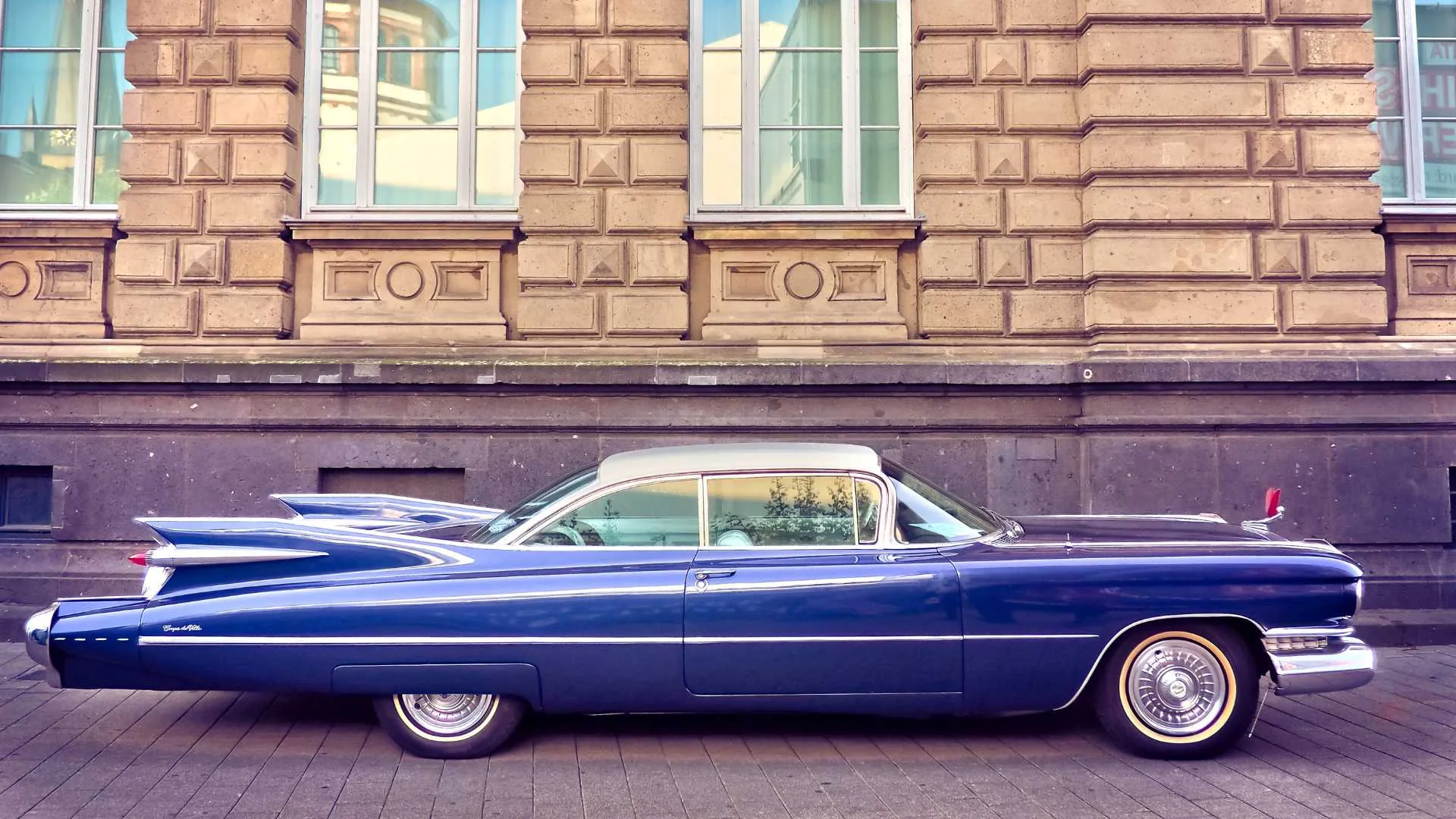 Blue classic car parked in front of a building